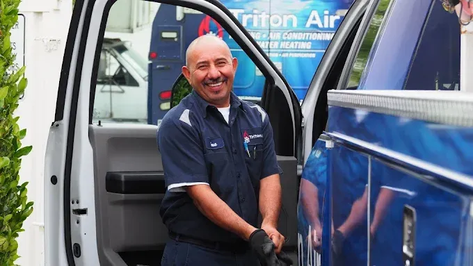 Triton Air & Plumbing technician preparing for service at a home
